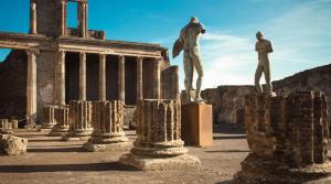 two statues of men standing on pedestals in front of a building at Hotel Apollo in Pompei