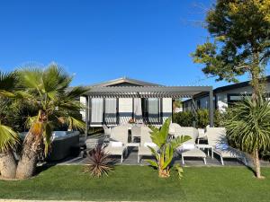 eine Terrasse mit weißen Stühlen und Bäumen sowie ein Haus in der Unterkunft Holiday Marina Resort in Grimaud