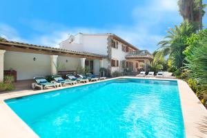 a swimming pool with chairs and a house at Owl Booking Villa La Font - Relax with a Big Pool in Pollença