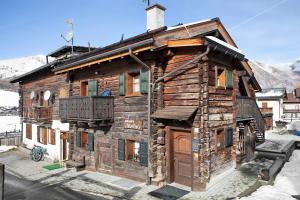 a wooden house with a balcony in the snow at Chalet Maffins 1 in Livigno