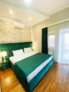 um quarto com uma grande cama verde num quarto em Hotel Orange Kutaisi em Kutaisi