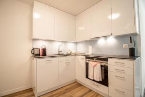 a kitchen with white cabinets and a sink at Rehwiesa Studio C04 in Arosa