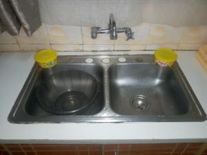 a stainless steel sink with two cups in it at The Red Nest Nahashon Kimemia One Bedroom in Nairobi