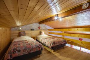 two beds in a room with wooden walls at La Tomba Val-Cenis Lanslevillard in Lanslevillard