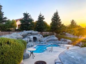 a pool in a backyard with rocks and a table and chairs at Sun Outdoors Central Coast Wine Country in Paso Robles