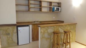 a kitchen with a counter and two bar stools at Apartamentos Mykonos in Las Toninas