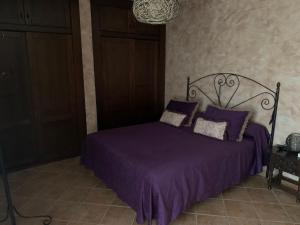 Una cama con sábanas y almohadas moradas en un dormitorio. en Maroteras, en Maroteras