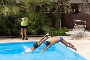 duas pessoas estão a mergulhar numa piscina em Hotel Continental em Rimini