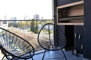 ein Paar Stühle auf einem Balkon mit einem Fenster in der Unterkunft Loi Flats Edificio Tucuman in Neuquén
