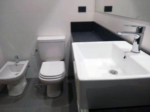 ein Badezimmer mit einem weißen WC und einem Waschbecken in der Unterkunft Loi Flats Edificio Tucuman in Neuquén