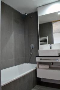 ein Badezimmer mit einer Badewanne, einem Waschbecken und einem Spiegel in der Unterkunft Loi Flats Edificio Tucuman in Neuquén