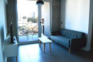 ein Wohnzimmer mit einem Sofa, einem Tisch und einem Fenster in der Unterkunft Loi Flats Edificio Tucuman in Neuquén