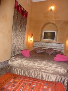 a bedroom with a large bed with pink pillows at Riad Jade Mogador in Essaouira