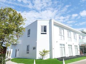 a white building with a tree in front of it at All Want Stay in Ch'ang-p'ing