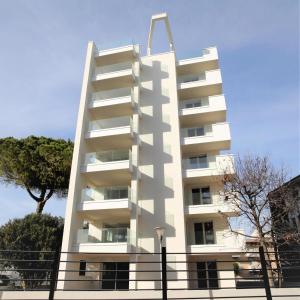 a tall white apartment building with a fence around it at Zero5.Zero5 in Lignano Sabbiadoro