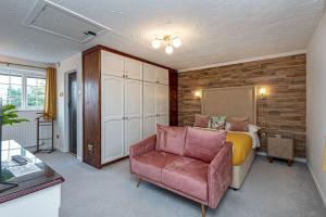 a bedroom with a bed and a couch and a chair at Felin Traeth Cottage in Rhosneigr