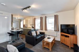 a living room with a couch and a flat screen tv at Swan Place Apartments By Viridian Apartments in Swindon