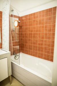 y baño con ducha y bañera de azulejos de color naranja. en Charmant appartement pour un sejour pour 4 a la Flotte en La Flotte