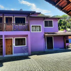 a purple house with a balcony on a street at Curral Beach in Ilhabela