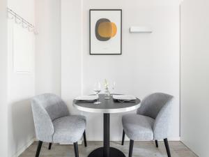 a white dining room with a table and two chairs at numa I Blau Apartments in Frankfurt/Main