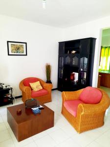 Una sala de estar con dos sillas y una mesa de café. en Charming Apartment in Flic en Flac – 50m² with Pool, en Flic en Flac