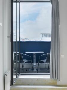 Puerta de cristal con mesa y sillas en el balcón en numa I Blau Apartments en Frankfurt