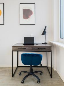 una scrivania con sedia blu e un computer portatile. di numa I Blau Apartments a Francoforte sul Meno