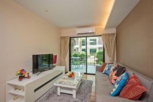 a living room with a couch and a tv at The Title Condo by Tropiclook in Rawai Beach