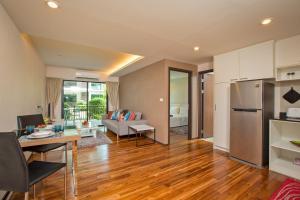 a kitchen and a living room with wooden floors at The Title Condo by Tropiclook in Rawai Beach