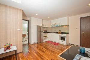 a kitchen with white cabinets and a wooden floor at The Title Condo by Tropiclook in Rawai Beach