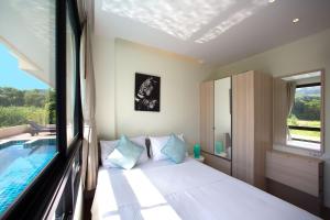 ein Schlafzimmer mit einem Bett und einem Pool in der Unterkunft LAGO APARTMENTS BY TROPICLOOK in Nai Harn Beach
