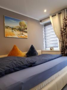 Schlafzimmer mit einem Bett mit blauer Bettwäsche und einem Fenster in der Unterkunft Apartment Luxus "Akzente-Art Minden" in Minden
