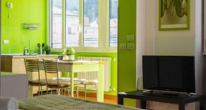 uma cozinha com paredes verdes, uma mesa e uma televisão em JOIVY Vibrant Studio Near Train Station em Como