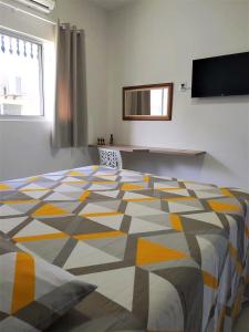 um quarto com uma cama grande com um padrão amarelo e cinzento em EcoFlat Fiore I em Paripueira