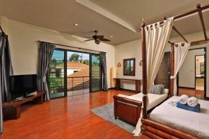 a bedroom with a bed and a television and a balcony at VILLA SALIKA | 4 bedroom Thai Balinese private pool villa | Rawai in Rawai Beach