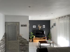 アネロンにあるMaison entière 4 lits 8 pl avec jacuzzi proche du safari de Peaugresのソファとテレビのあるリビングルーム