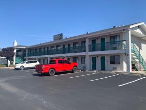 un camion rouge garé dans un parking devant un bâtiment dans l'établissement GreenTree Inn of Holbrook, AZ, à Holbrook