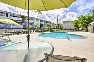 a table with an umbrella next to a swimming pool at Lanai and Community Pool Access Sunny Central Condo in Kailua-Kona