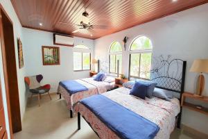 a bedroom with two beds and a chair and windows at LA BUENA VIDA CONDO in Tamarindo +29 photos