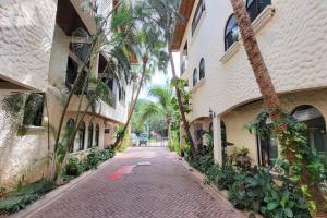 a cobblestone street with palm trees next to a building at LA BUENA VIDA CONDO in Tamarindo