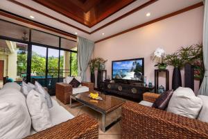 sala de estar con muebles blancos y TV en VILLA RAAS | Private Pool | Baan Bua Estate by Tropiclook | Naiharn beach, en Nai Harn Beach