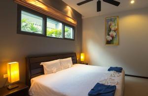 a bedroom with a white bed with two windows at VILLA ARUHE | 2 Bedroom Private Pool Villa in Popular Onyx Villas | 3 min to Naiharn Beach in Rawai Beach