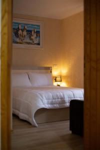 ein Schlafzimmer mit einem weißen Bett und einem Gemälde an der Wand in der Unterkunft Vila Lika in Korçë