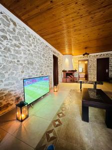 a living room with a large screen tv in a stone wall at BUJTINA CAKULI, Rehovë - ERSEKË in Rehovë