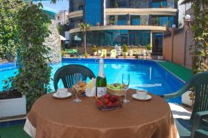 un tavolo con una bottiglia di vino e frutta accanto alla piscina di Ekipazh Hotel ad Adler