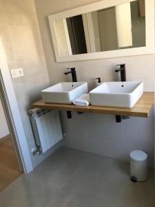 a bathroom with two white sinks and a mirror at La Casita del Alcázar in Medina de Pomar