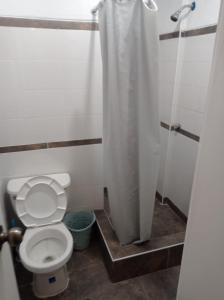 a bathroom with a toilet with a shower curtain at HOSTAL PARIS in Piura +8 photos