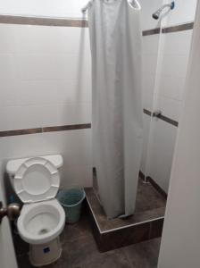 a bathroom with a toilet with a shower curtain at HOSTAL PARIS in Piura