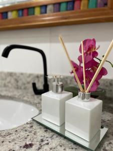 a bathroom counter with two vases with flowers in them at BOA SORTE SUITES com PISCINA, GARAGEM GRATIS e Pé na PRAIA de GERIBÁ in Búzios