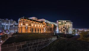 um edifício é iluminado à noite numa cidade em Le Capitole Hotel em Cidade de Quebec